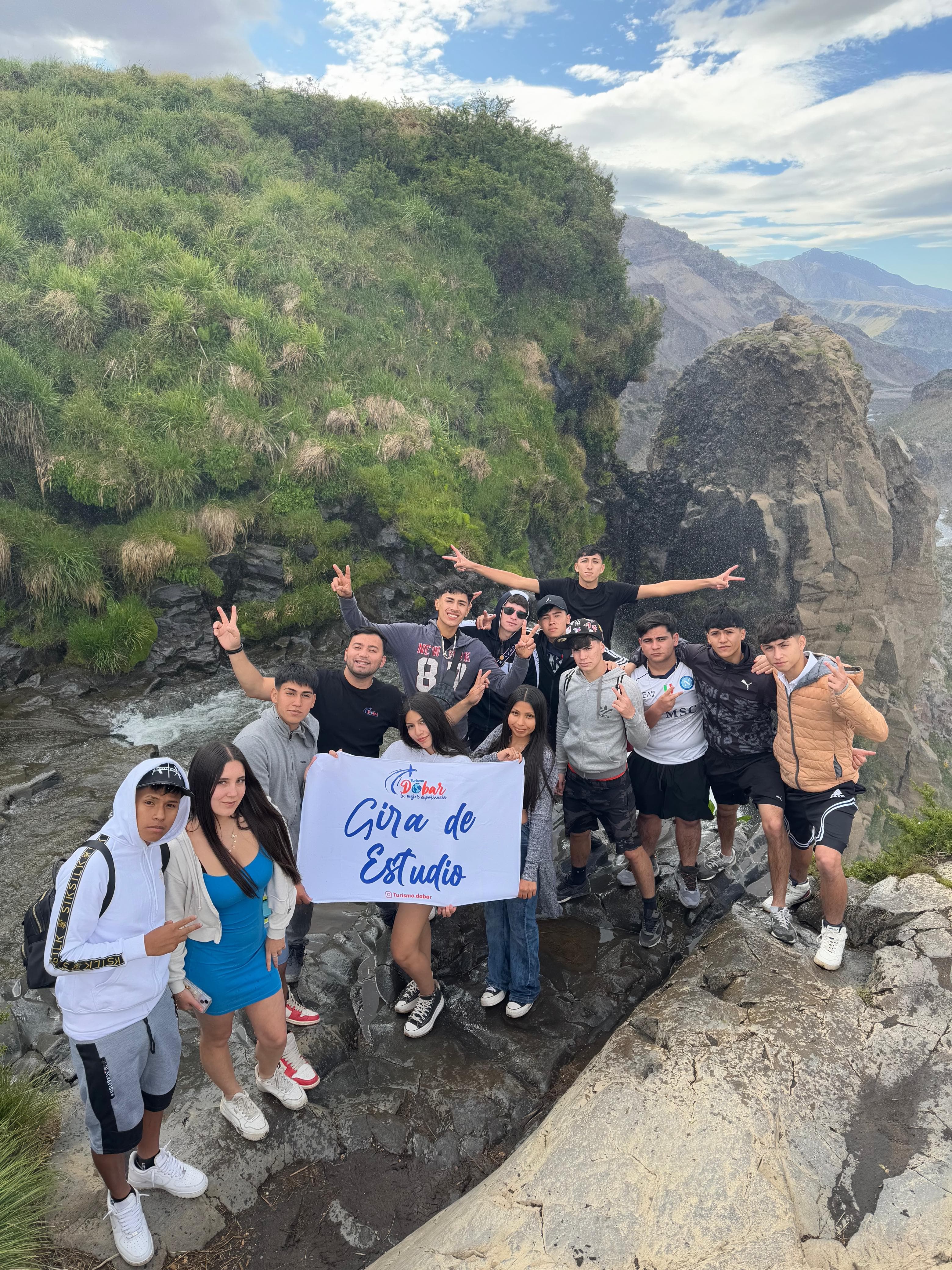 Grupo de gira de estudio con banner de Turismo Dabar en la montaña