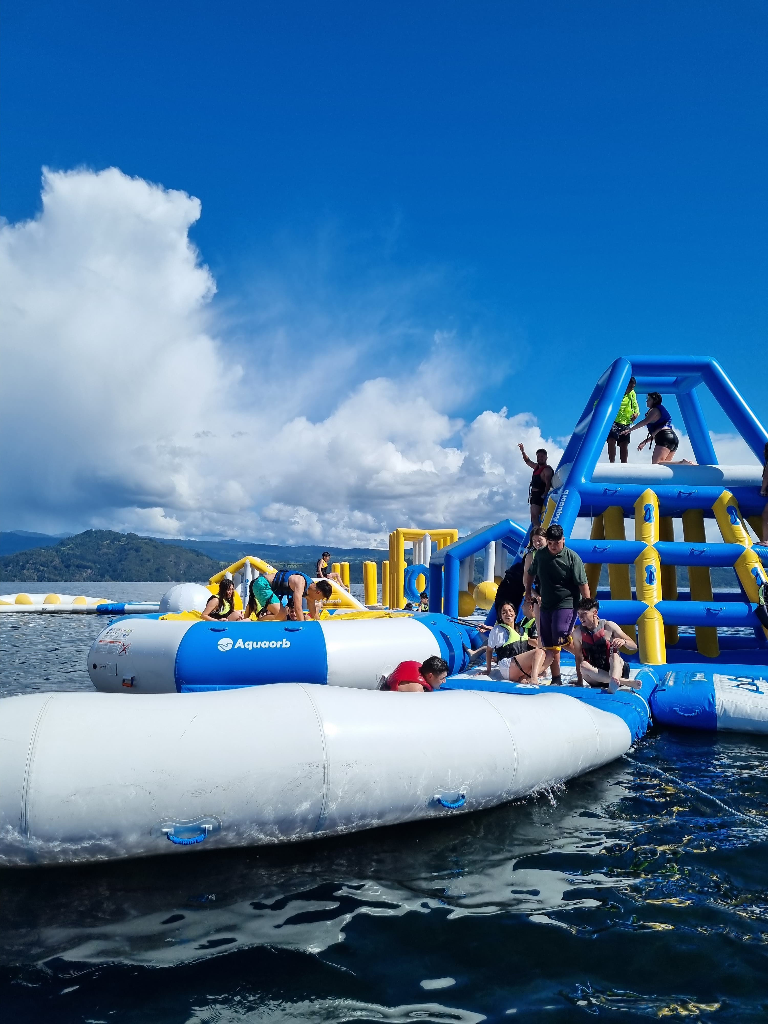 Estudiantes disfrutando un parque acuático inflable en el lago